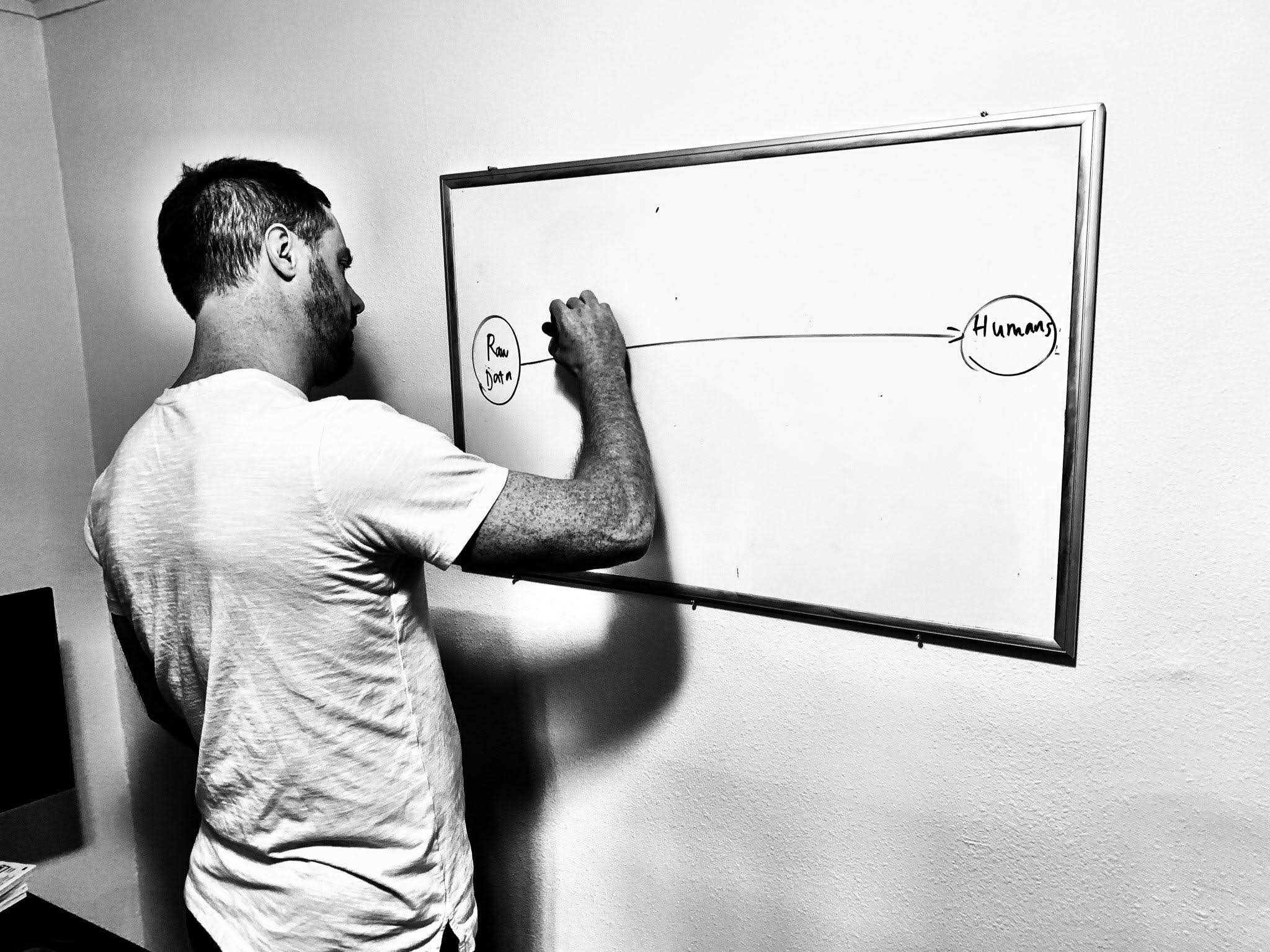 Black and white picture of Austin Senseman writing on a whiteboard.