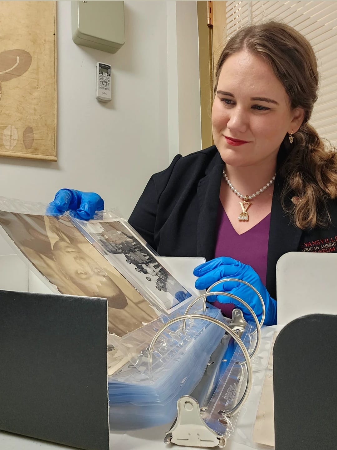 Tory Schendel-Vyvoda, Curator, wearing blue nitrile gloves and browsing through the newly rehoused photographs. Image courtesy of the Evansville African American Museum