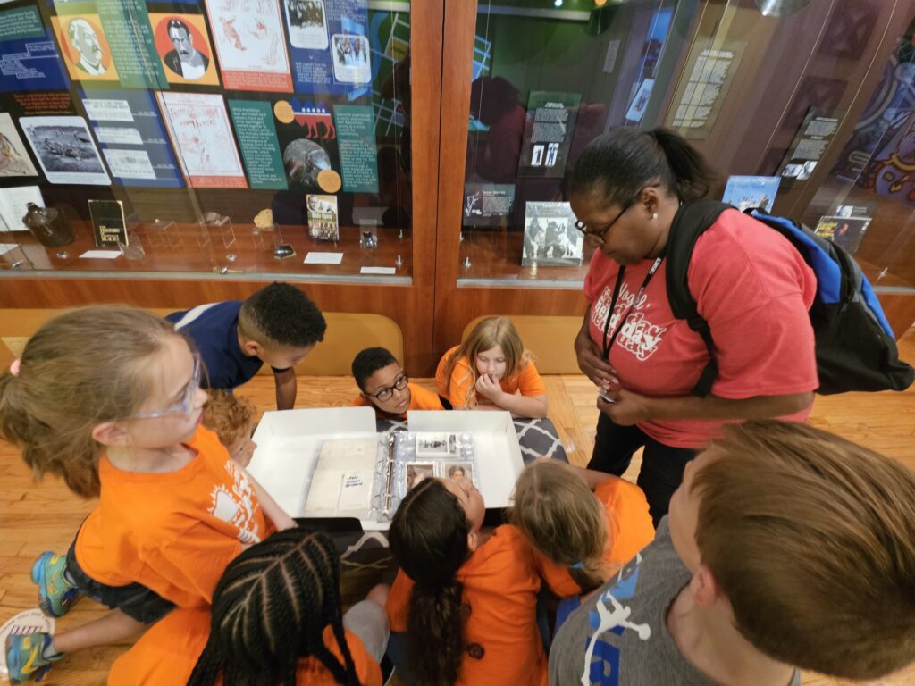 Hebron Summer Camp students crowded around Evansville African American Museum photograph collection in its new clamshell enclosure.