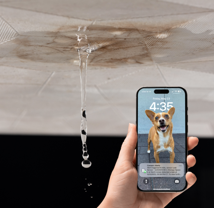 Leak Detection Alert A phone showing a leak detection alert in front of a leaking ceiling